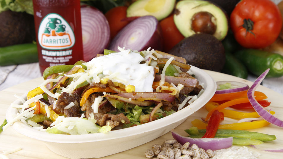 Family-style Mexican food spread with rice, beans, tacos, and guacamole on a festive table